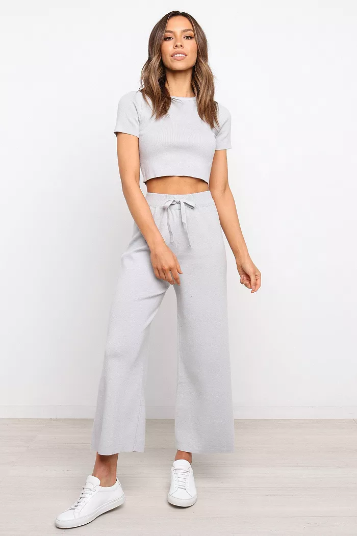 A woman wearing a matching grey short sleeved shirt and pants