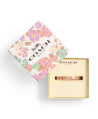 A gold bracelet in a box with a floral top