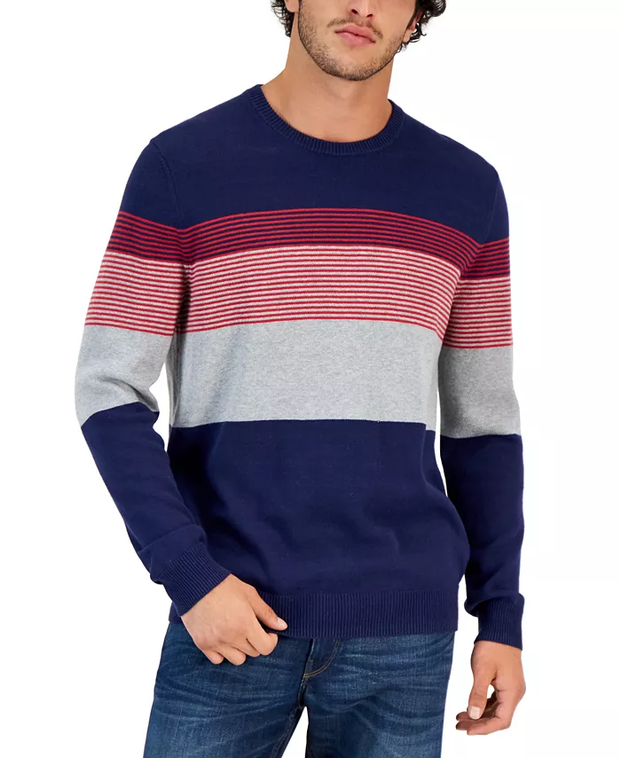 A man wearing a Navy Blue Club Room Striped Sweater with red stripes and grey blocks around the sweater and a pair of blue jeans