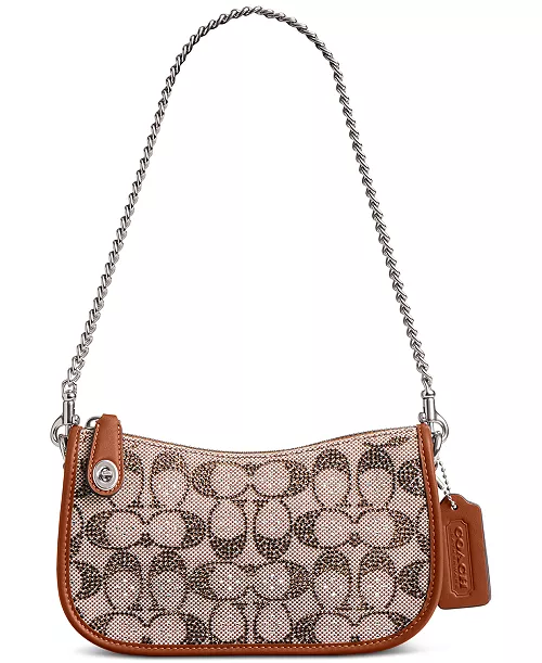A stylish shoulder bag featuring a tan leather trim and a chain strap, with a patterned fabric showcasing an elegant interlocking design.